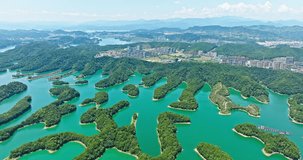 Aerial video of clear lake water and green island with mountain natural landscape in Hangzhou. Drone shooting backwards.