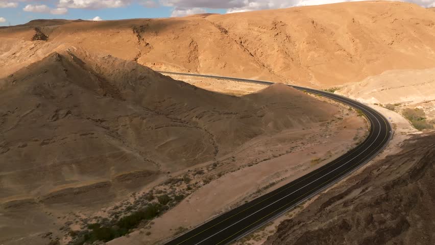 Car zooming by heading north on a Desert highway with cloudy blue sky