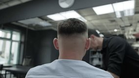 A young man gets up from his chair in a barbershop after getting a haircut. Stylish and fashionable haircut. Slow motion