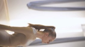 Sporty woman doing stretching dance in a mirror room, performs a dance with fabric ropes, vertical video for social networks.