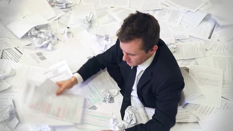 the man in the office drowning in paper