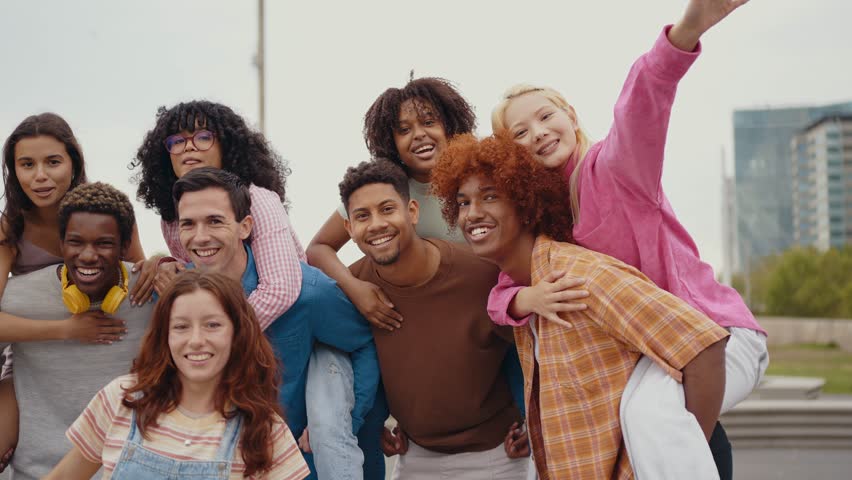 Group of multiethnic teenagers having fun outdoor. Campus students hanging out in the city center