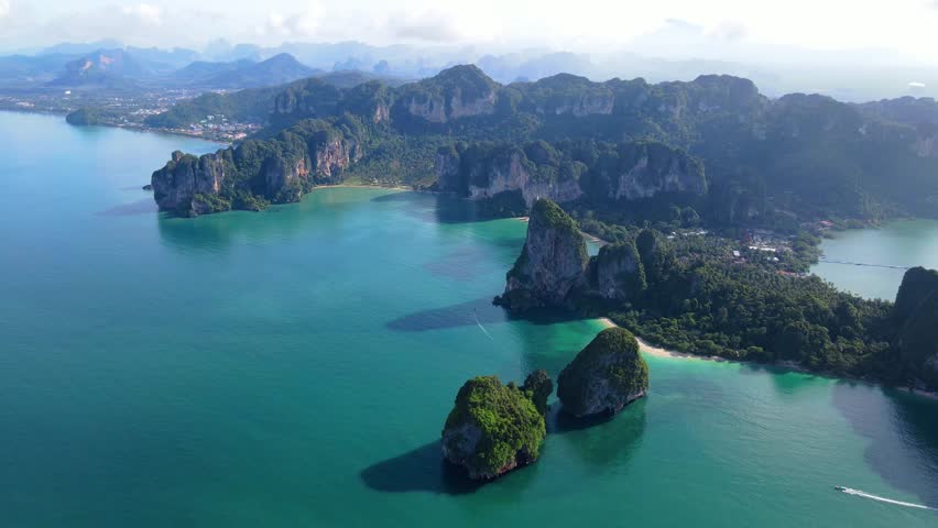 Railay Beach Krabi Thailand a tropical beach with a turqouse colored ocean, view from a drone of idyllic Railay Beach in Thailand in the evening at sunset with a cloudy sky Royalty-Free Stock Footage #3430035455
