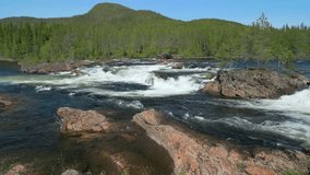 A low-flying drone video reveals the foamy rapids of Namsen River in Trondelag, Norway, surrounded by dense greenery and tranquil landscapes