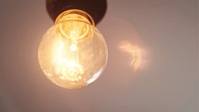 Incandescent bulb turns on, and off and flickers on white background, a place for text. Warm flashing filament close-up. Glass old bulb glowing yellow warm light. Tungsten lamp light. Idea, Copy space - Powered by Shutterstock - Get 15% off with code: PIKWIZARD15