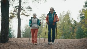 Senior hikers man woman hiking on nature autumn park holding sticks talking enjoying landscape. Tourists man woman trekking carrying backpacks with touristic equipment. Nordic walk travel tourism. - Powered by Shutterstock - Get 15% off with code: PIKWIZARD15
