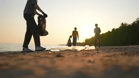 Silhouettes of volunteers guys collecting trash garbage on ocean coast at sunset. Ecology environment protection. Putting trash, rubbish, waste in plastic bags. Blur video shot, sand in focus. - Powered by Shutterstock - Get 15% off with code: PIKWIZARD15