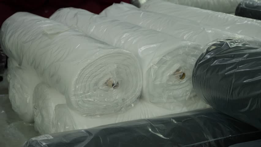 Close-up of fabric rolls wrapped in plastic for manufacturing.
