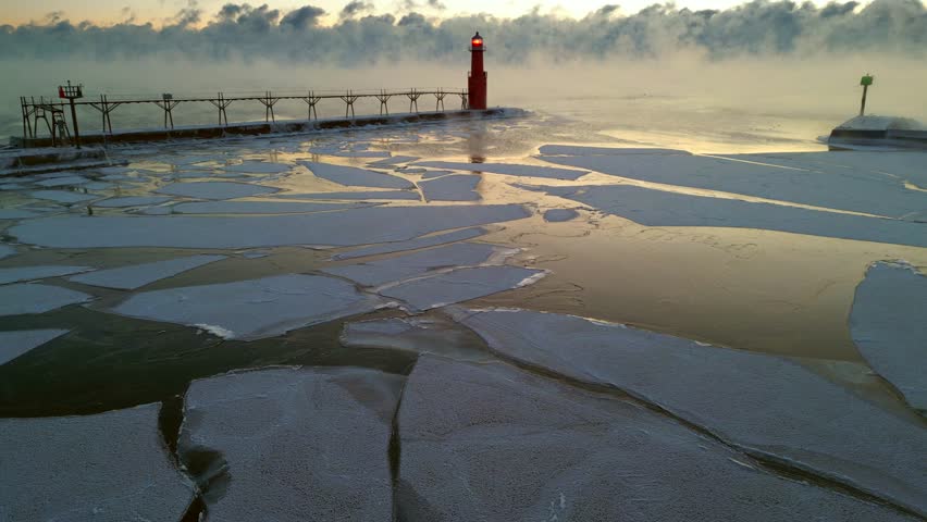 Dramatic Winter twilight over steaming Lake Michigan with stunning Lighthouse keeping solitary watch over icy harbor.