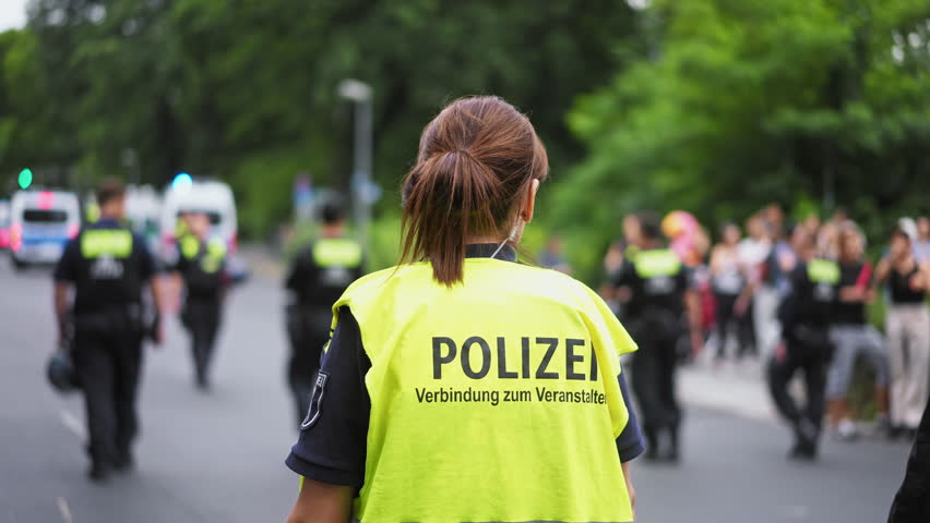 Brave police woman patrol city street. Policewoman wear yellow life vest. Feminist girl do dangerous male job. Feminism concept. Female officer help people. Cop lady walk urban road. 911 keep order.