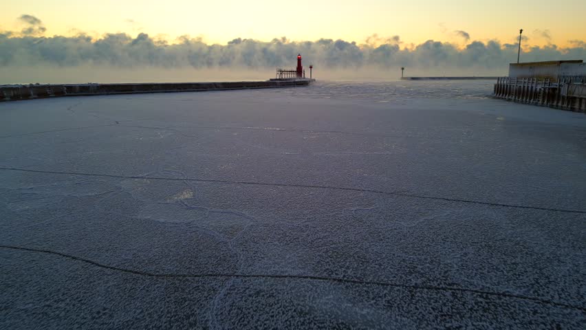 Dramatic Winter twilight over steaming Lake Michigan with stunning Lighthouse keeping solitary watch over icy harbor.