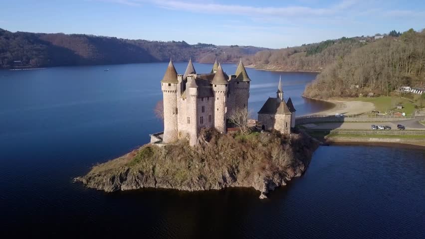 drone shot around chateau de val, french castle on the shore of the artificial lake of bort les les orgues on a sunny day during winter, Cantal departement, auvergne rhone alpes region, france