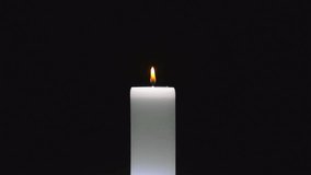 Small red flame flickers from white cylindrical candle rotating as wax pools and drips on black background - Powered by Shutterstock - Get 15% off with code: PIKWIZARD15