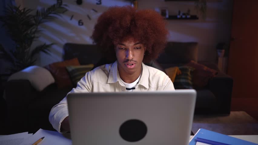 Front view of an overwhelm young African american male studying late from home using a laptop, typing frustrated by not understanding the online class. Royalty-Free Stock Footage #3430382787