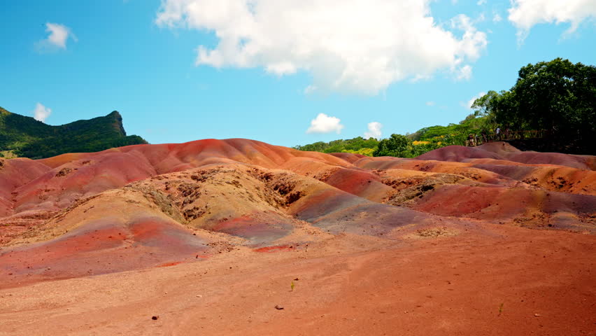 Wide shot of the Seven Colored Earths Chamarel national park in the Mauritius Island. Traveling fluffy clouds. Vibrant colors, sand dunes. Touristic attraction. Terres des Sept Couleurs.