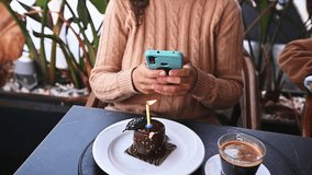 Close-up of a birthday girl holding mobile phone and photographing or recording video of her birthday cake with a candle, while celebrating happy life event outdoors - Powered by Shutterstock - Get 15% off with code: PIKWIZARD15