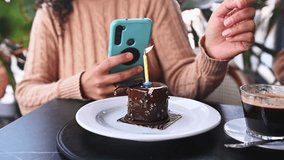 Curly haired happy young woman, a birthday girl taking photo, photographing her birthday cake, blowing candle and making cherished wish on her birthday party. People. Lifestyle. Festive life events - Powered by Shutterstock - Get 15% off with code: PIKWIZARD15