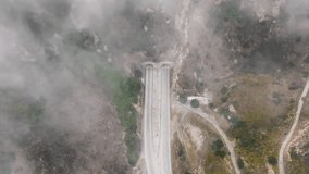Top view of Kanan road poking through fog in morning, Malibu, Los Angeles suburban, California, USA. Aerial view of tunnel in Santa Monica Mountains. Cloud formations covering highway, 4k footage