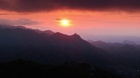 Aerial view of sun setting over the Malibu mountains, California, USA. Breathtaking landscape at the sunset. Colorful sky with clouds. Silhouette of rocky Santa Monica mountain range, 4k footage 