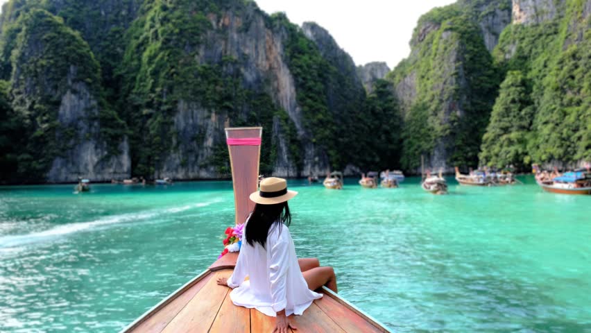Asian women in front of a longtail boat at Kho Phi Phi Thailand, women in front of a boat at Pileh Lagoon with turqouse colored ocean during a boat trip to Maya Bay Koh Phi Phi  Royalty-Free Stock Footage #3430518033