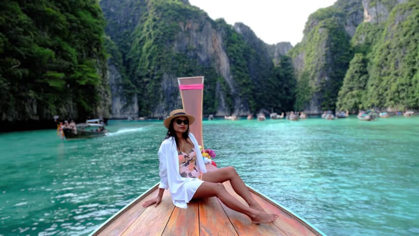 Asian Thai women in front of a longtail boat at Kho Phi Phi Thailand, women in front of a boat at Pileh Lagoon with turqouse colored ocean during a boat trip to Maya Bay Koh Phi Phi  Royalty-Free Stock Footage #3430524727