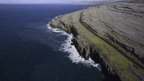 Ocean wave hit rough stone coastline of Ireland in county Clare. Aerial shot on stunning nature scenery with cliff and ocean. Popular tourist area with amazing Irish nature scenery