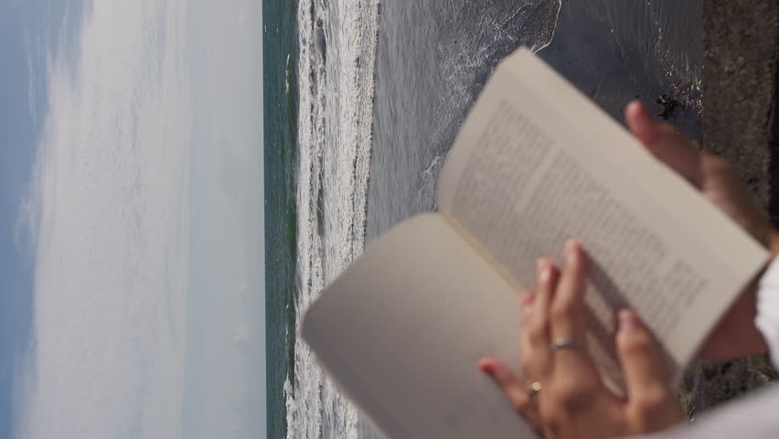 book in hands on the background of the ocean and waves. Vertical video Royalty-Free Stock Footage #3430663293