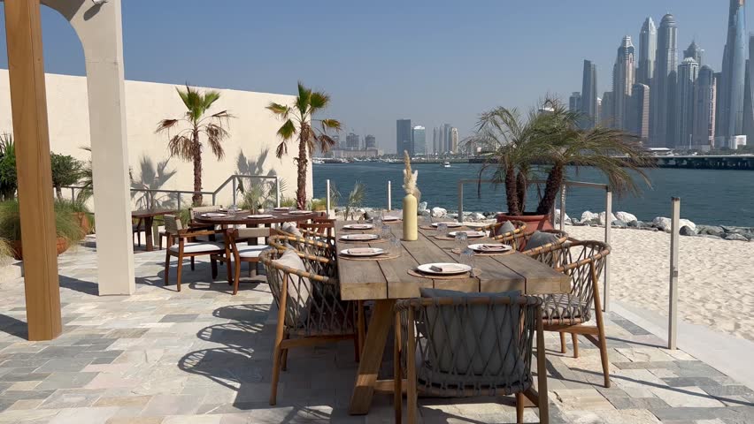 Dubai Jumeirah beach with marina skyscrapers in UAE. Luxurious sandy beach in the Dubai Marina area with views of the iconic skyscrapers. Beaches and Dubai eye view at sunset with boats and yachts.