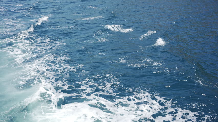 4K Rear view of a boat passing the ocean with white foam from water waves. Passenger high-speed boat floating in deep blue sea. Travel nature on summer, water transportation and tourism concept.