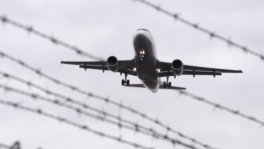 Airplane landing flies over barbed wire - slow motion