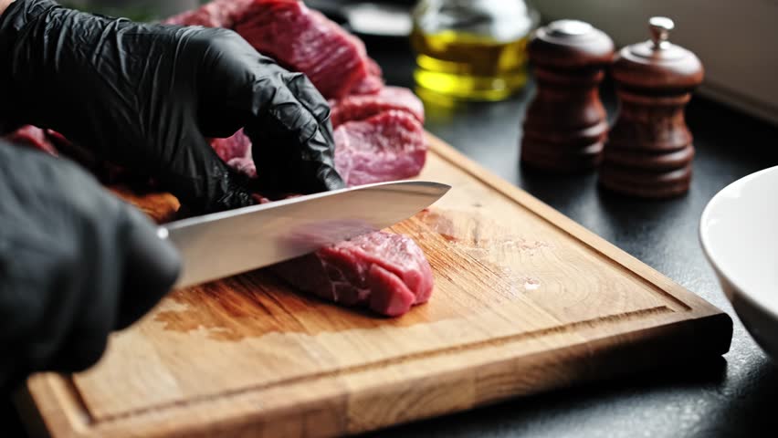 Slicing raw meat on a wooden cutting board in the kitchen. Raw beef meat, cooking process, stock video footage 4k.