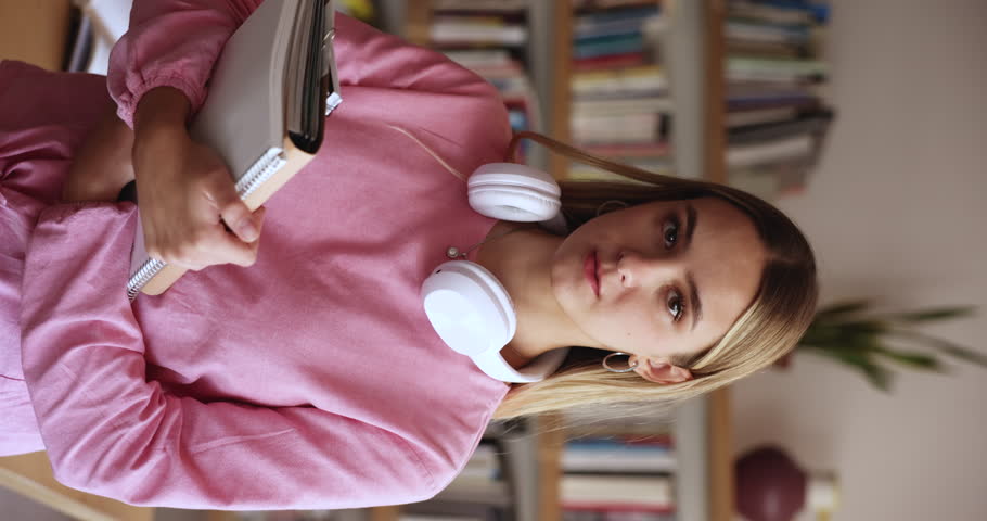 Portrait of attractive teenager student girl holding workbooks posing in classroom, visit high school library for exams preparation, looking motivated to gain new knowledge enjoy university education Royalty-Free Stock Footage #3430797761