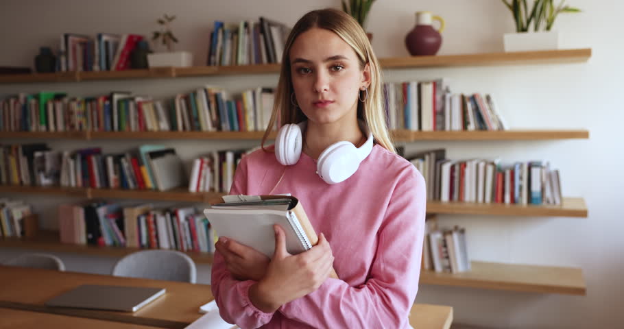 Portrait of attractive intelligent female student posing in campus library, holding textbooks and workbooks smile looking at camera enjoy high school studies, feels satisfied with university education Royalty-Free Stock Footage #3430817521