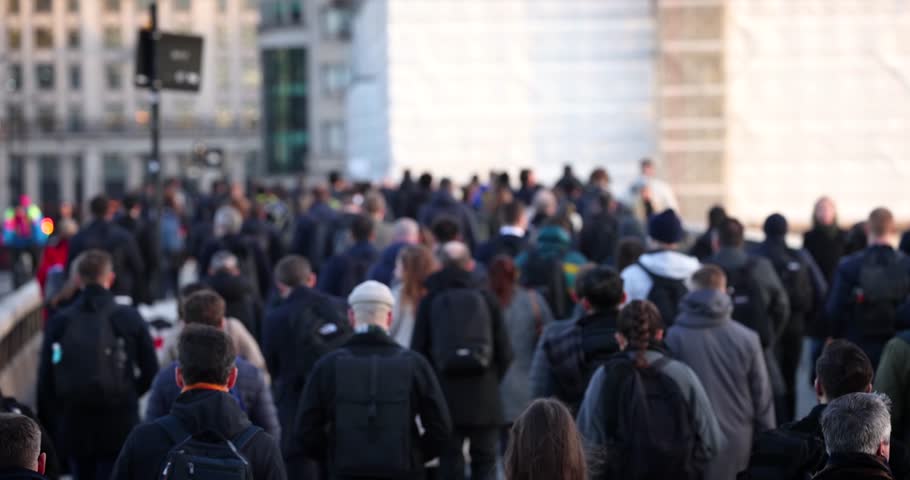 Slow motion shallow focus view of a large crowd of commuters going to work in the City during morning time, London, England