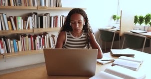 Pretty African girl studying on-line sit at desk using laptop, video calling to tutor or schoolmate, prepare for exams, take part in virtual meeting, gains news skills, share information. Education