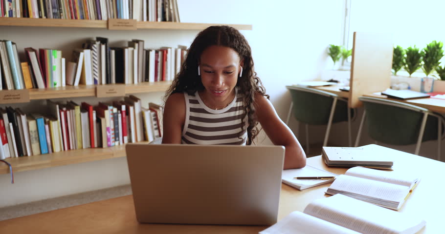 Pretty African girl studying on-line sit at desk using laptop, video calling to tutor or schoolmate, prepare for exams, take part in virtual meeting, gains news skills, share information. Education Royalty-Free Stock Footage #3430852091