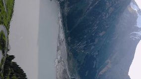 Vertical video footage top view of Big Almaty Lake and serpentine road. The water in the lake is cloudy due to active melting of glaciers in summer