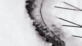 Vertical video footage of a close-up of a bicycle wheel spinning in the snow. The bicycle does not move due to a thick layer of snow on the road. Slow Motion 2x