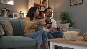 Adult couple man and woman caucasian husband and wife or boyfriend and girlfriend play console video games at home hold joystick controller have fun leisure joy and bonding concept