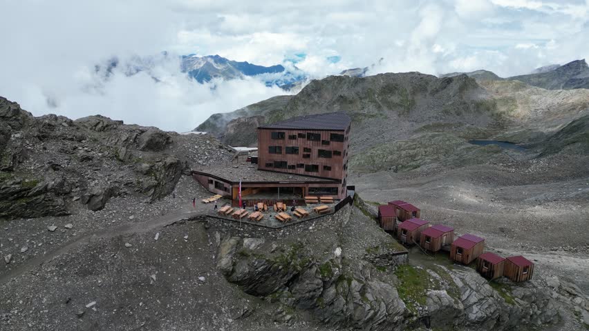 Flight over modern alpine hut Stettiner Hütte (Rifugio Francesco Petrarca) towards mountain panorama in Texel group, South Tyrol, Italy