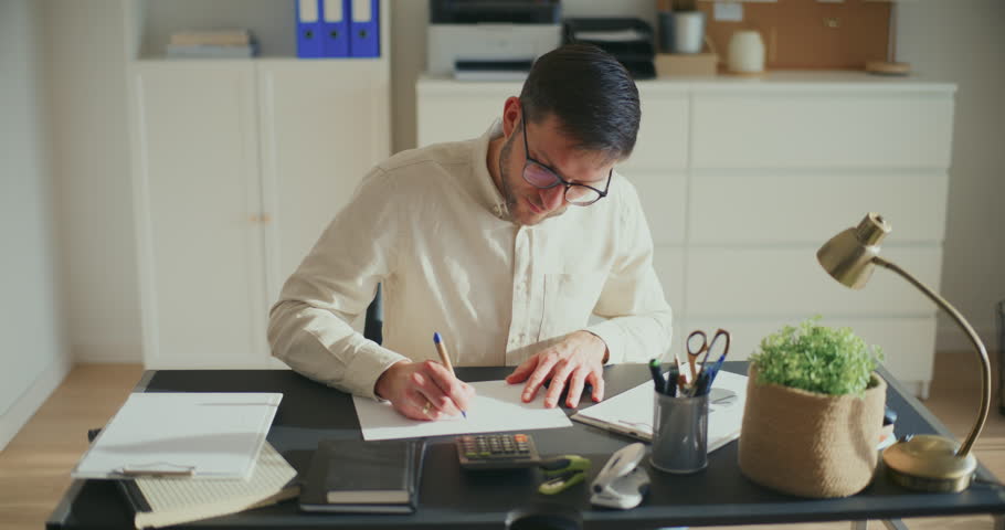 Angry male entrepreneur crumbling and throwing paper while working at desk in office