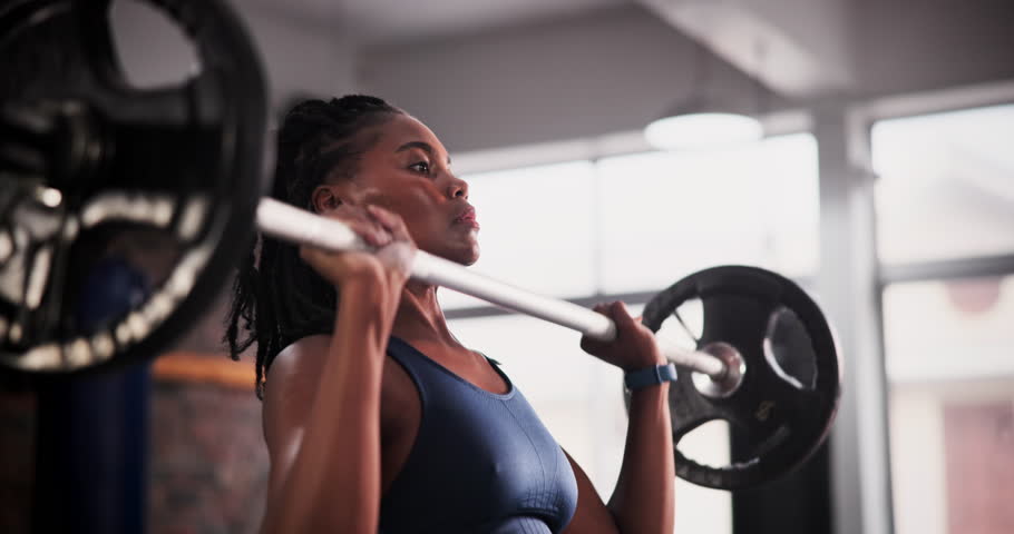 Weightlifting, fitness and black woman with muscle in gym for bodybuilder training, intense workout and exercise. Wellness, sports and person with barbell for challenge, strength and strong body