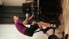 Man is training on stationary bicycle with smartphone in hands, typing messages, scrolling news in internet. Vertical video