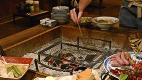 Grilling fish on a sunken hearth at a Japanese ryokan or other travel meal Family vacation