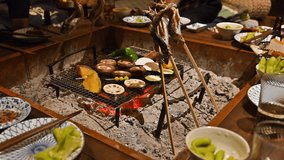 Grilling fish on a sunken hearth at a Japanese ryokan or other travel meal Family vacation