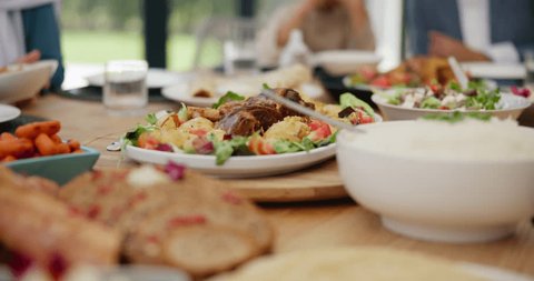 Table, healthy food or hands of family in home with lunch, drinks or celebration in social gathering event. Group of people, eating or plate closeup with dinner, meal or brunch with salad or bowl Video de stock