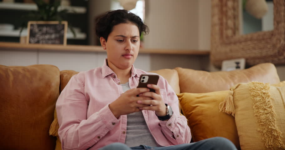 Woman, confused and stress on sofa with phone news, phishing mistake or financial scam at home. A young person with worry, doubt and reading of wrong information, fraud or balance check on her mobile Royalty-Free Stock Footage #3431121479