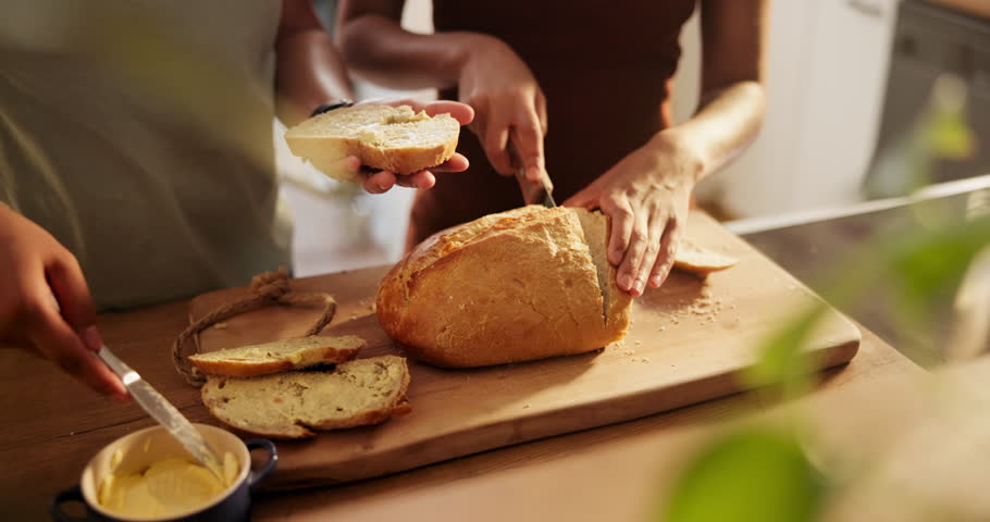 Couple, hands and cutting bread with butter, spread or roll for meal, snack or wheat in kitchen at home. Closeup of hungry people making food, morning breakfast or bun for healthy nutrition on table
