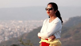4K Video : Young women of Indian ethnicity standing on hill and she looking Jaipur City, Rajasthan, India.        