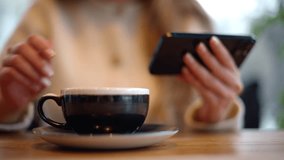 Woman drinking latte coffee while watching content on smartphone
